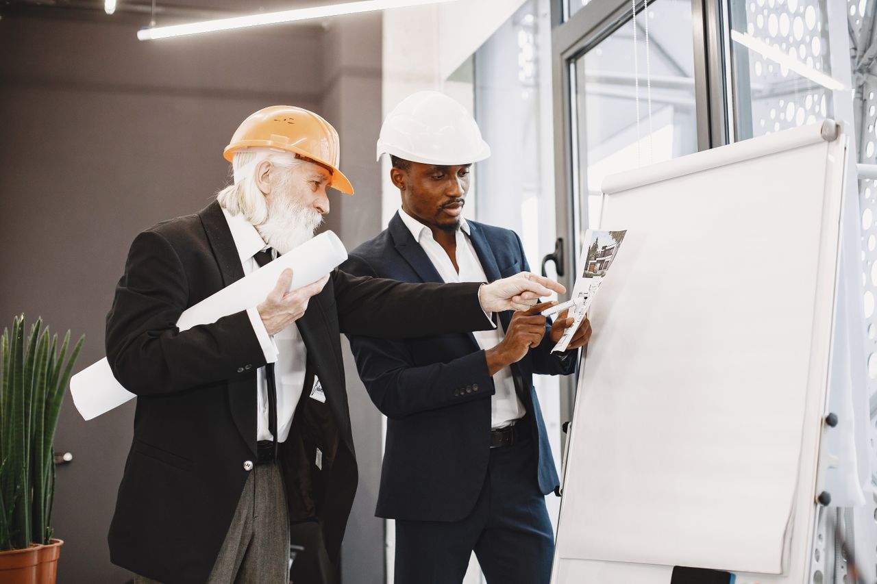Two engineers discussing blueprints in an office setting.